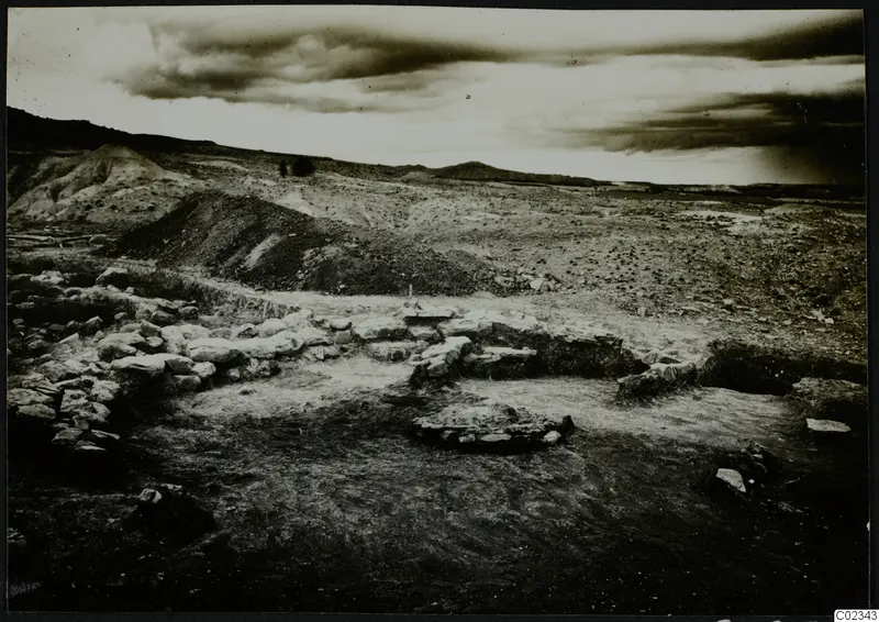Excavated stone wall foundations at Kythrea, with a spoil heap and hills behind