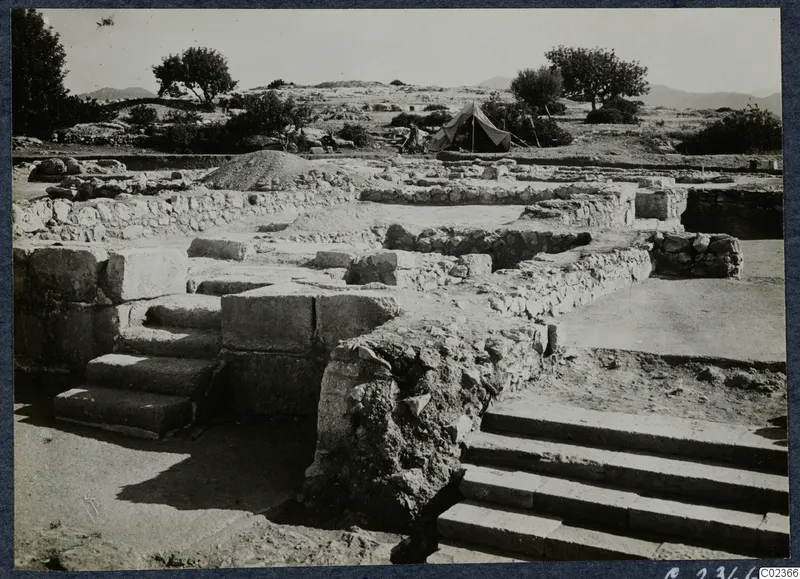 Excavated ruins at Vouni Palace with stone steps in the foreground and a tent among trees behind