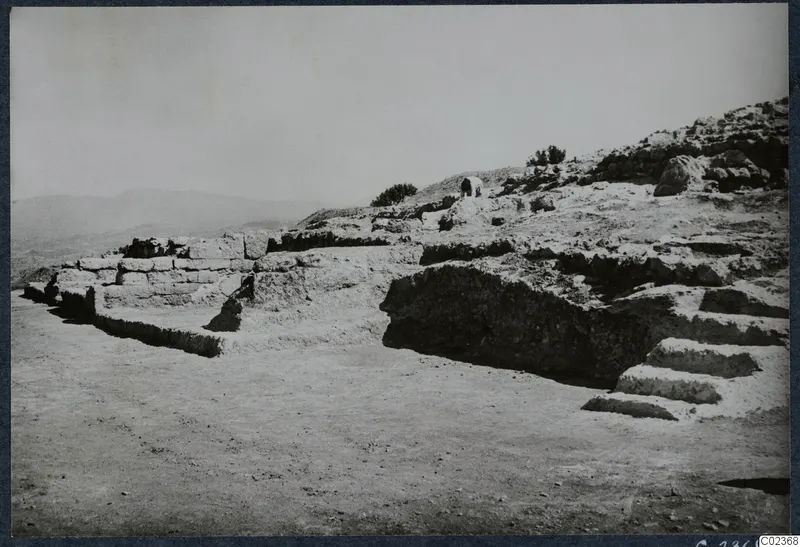 Ruined stone walls and a flight of steps on a rocky slope at Vouni, with hills in the distance