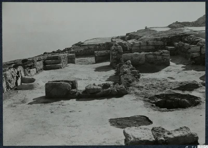 Excavated ruins of walls and stone foundations at the palace at Vouni, with a stone-lined basin on the left.