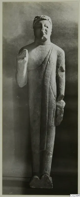 Standing limestone statue from Kition with broken arms, shown on a rectangular base.