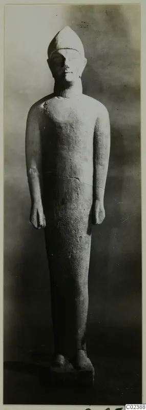 Limestone statue of a standing figure from Kition, with a tall pointed headdress and arms held at its sides