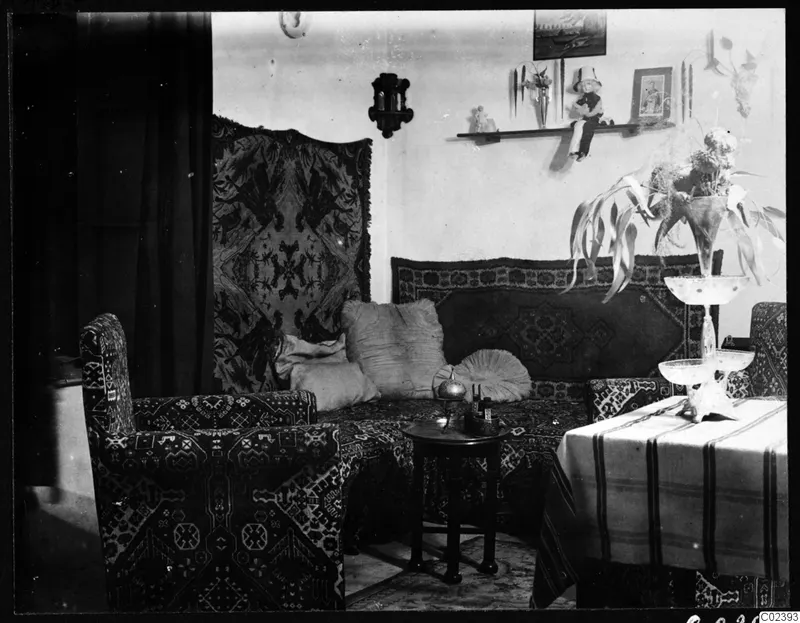 Sitting room in Chocolata's house with a patterned sofa, armchair, wall textile and a table with flowers