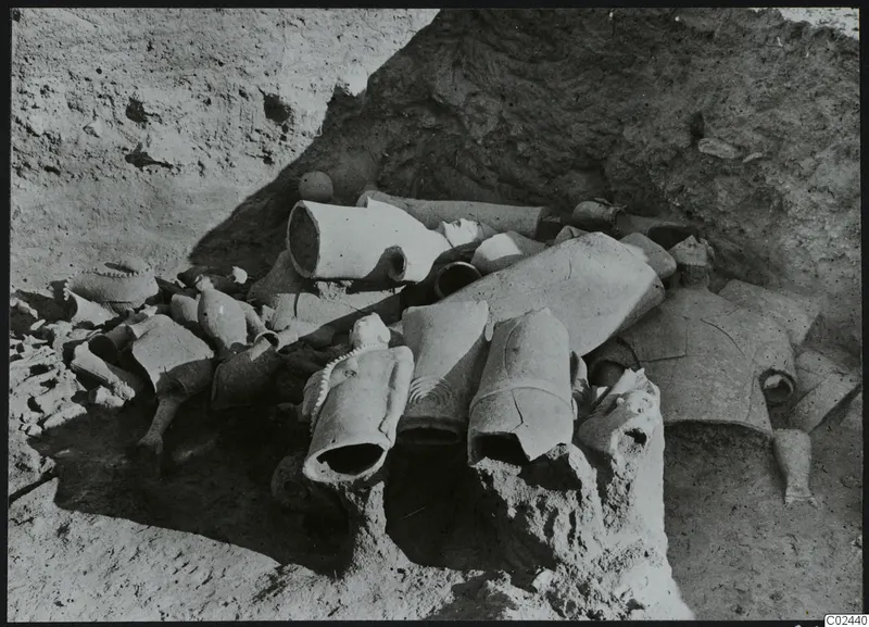 Broken figures and vessel fragments lying in situ in excavated soil at Ayia Irini