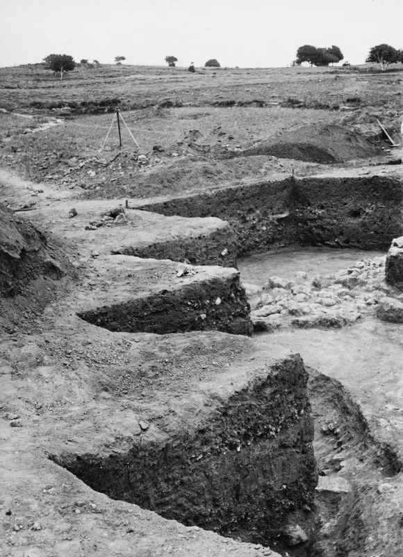 Stepped soil sections cut across a water channel in an excavation at Ayia Irini