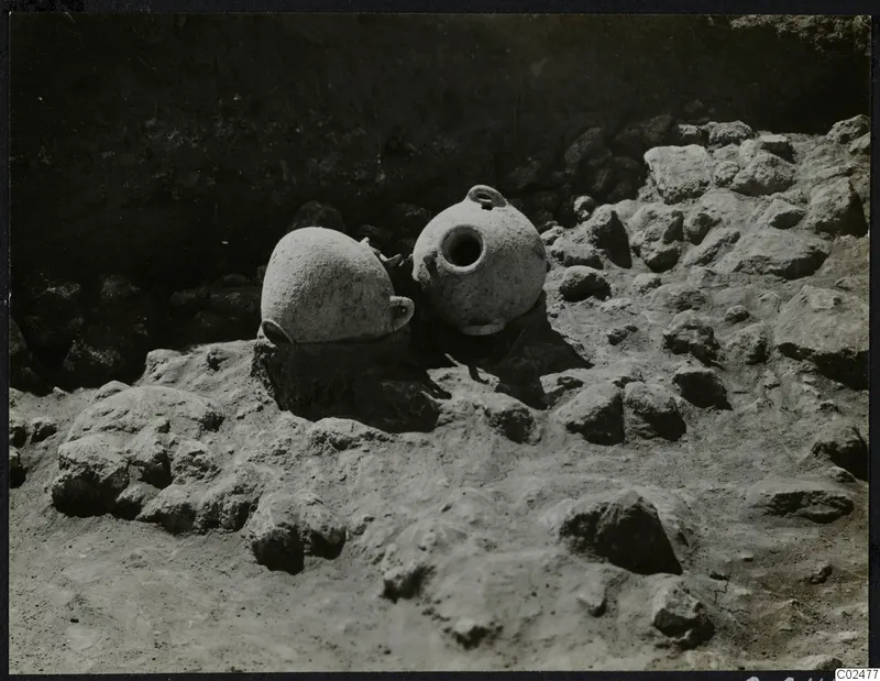 Two pottery vessels with small handles among stones in an excavation at Ayia Irini