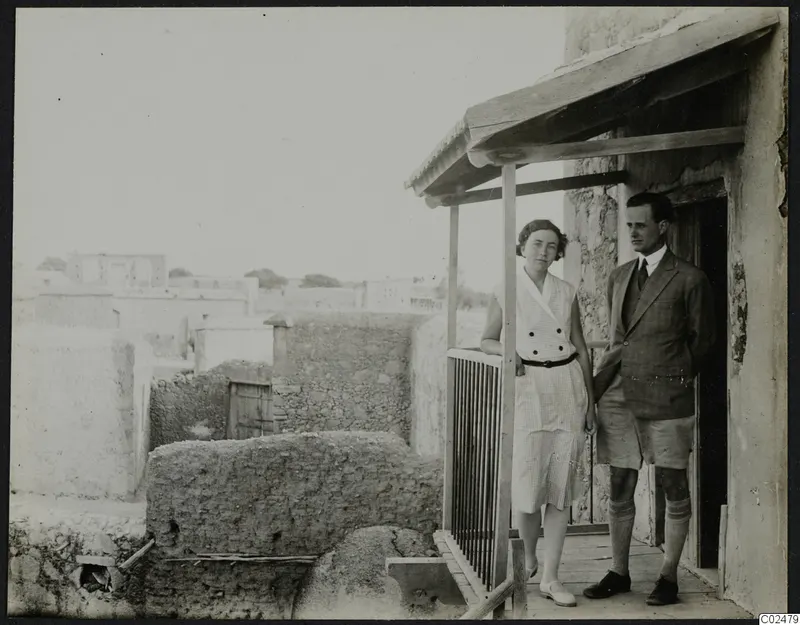 Einar and Vivi Gjerstad standing on a wooden veranda beside a stone and mud-brick building at Ayia Irini