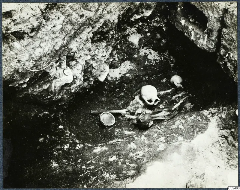 Skeletal remains in situ in a rock-cut hollow during excavation at Enkomi, with a vessel beside them