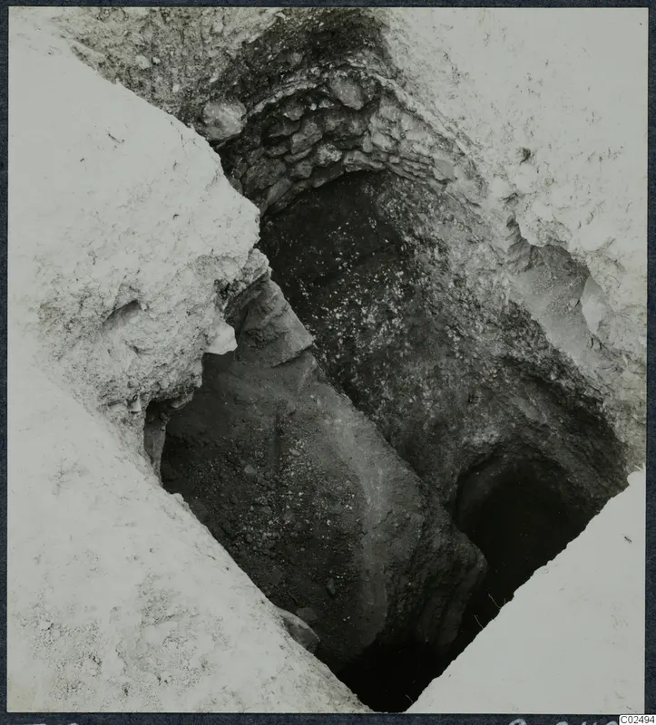 Excavated tomb entrance at Enkomi, with a stone-built wall above a sloping passage leading down to a dark opening
