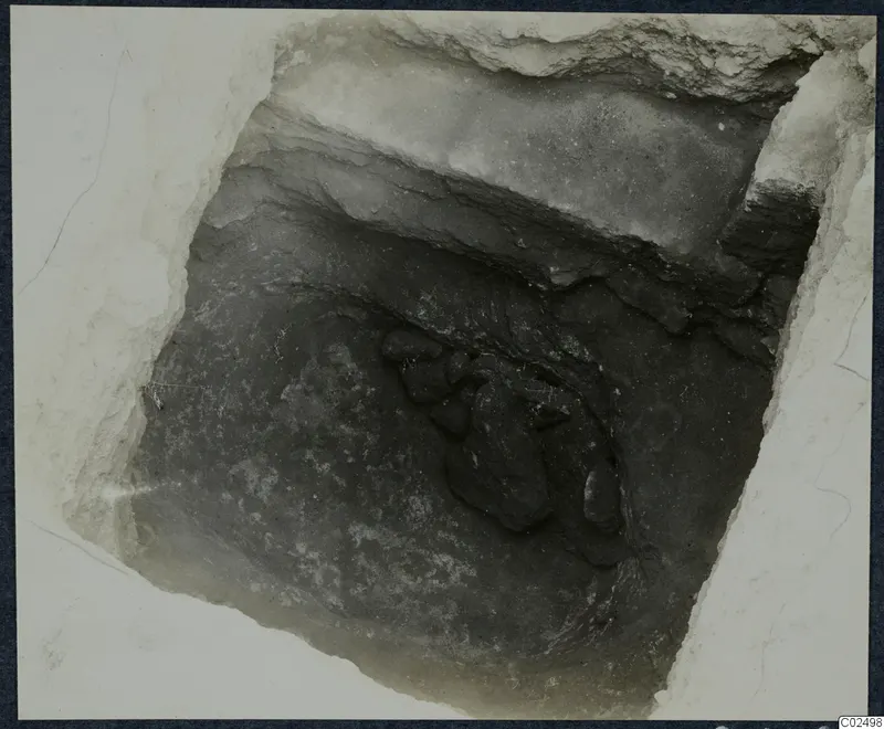Tomb 17 at Enkomi during excavation, looking down into the chamber at a cluster of dark stones