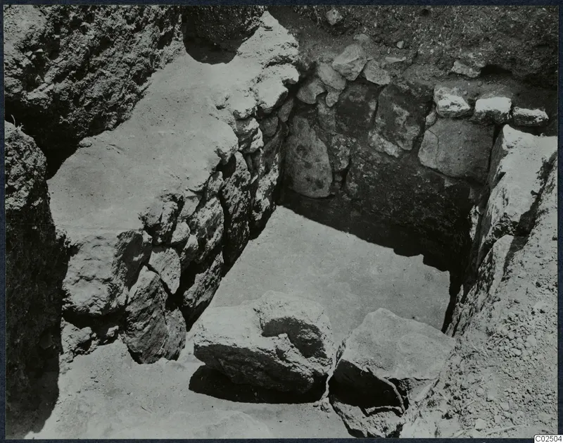 Tomb 5 at Enkomi during excavation: chamber with stone walls and large loose stones on the floor.