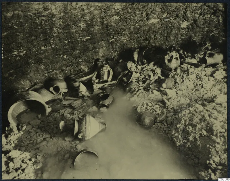 Tomb 2 at Enkomi: tomb chamber during excavation, with pottery vessels, skulls and bones lying in standing water.
