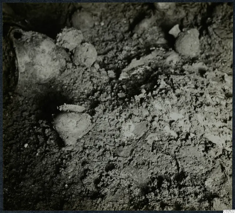 Tomb 11 at Enkomi during excavation, with pottery vessels lying in the soil of the tomb chamber.