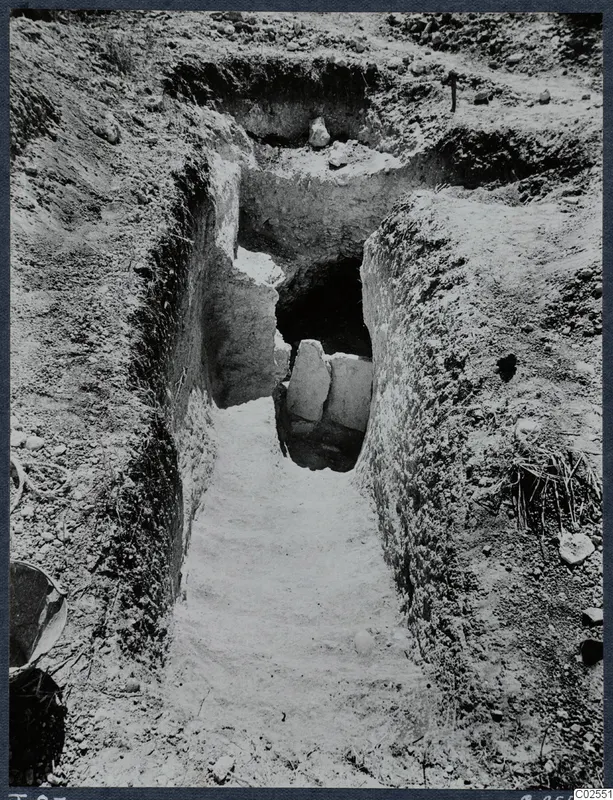 Sloping passage cut into earth leading to the entrance of Tomb 87 at Marion, with stone slabs at the opening.