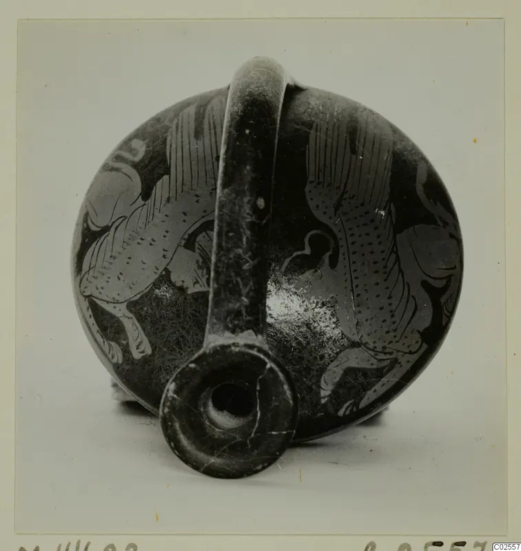 Dark-surfaced vessel with a strap handle and pale painted figures, mouth facing the camera