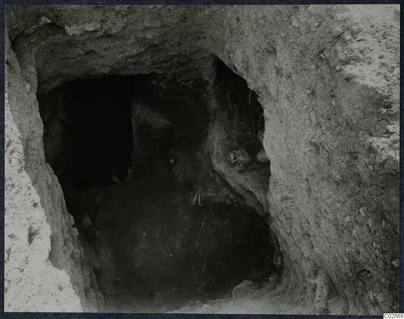 Tomb 19 at Enkomi: view through the excavated opening into the tomb chamber, with objects against the right wall.