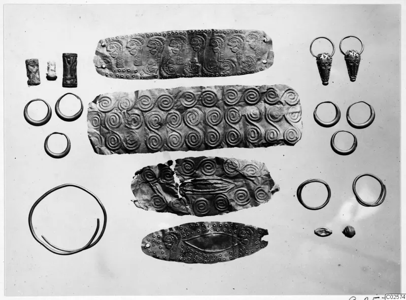 Gold and silver objects from Enkomi: embossed bands, earrings, rings and beads laid out on a pale background
