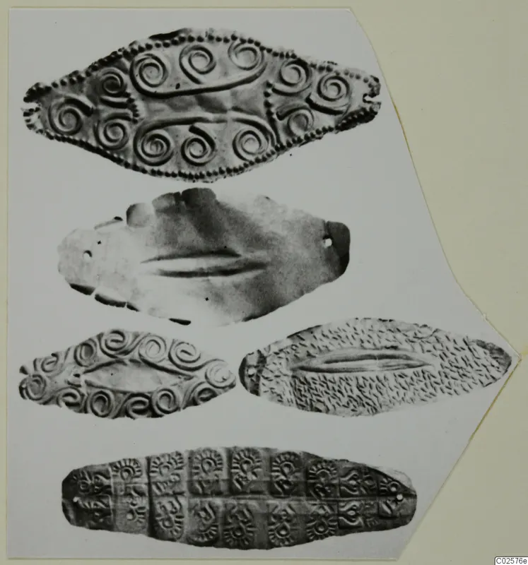 Five flat, leaf-shaped objects with spiral, dotted and stamped decoration, mounted on a pale card.