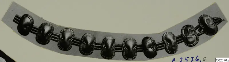 Curved necklace of ten rounded pendants strung on parallel cords, laid on a pale grey card