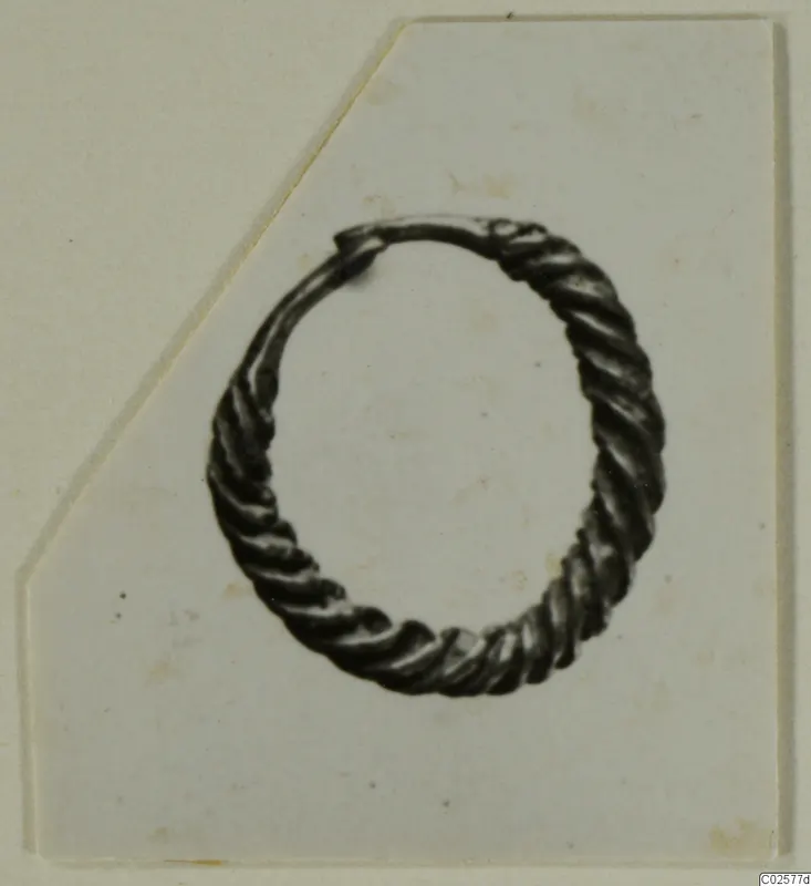 Twisted-wire ring earring from Enkomi, shown on a white card with one corner cut away