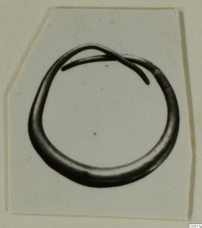 Earring from Enkomi: an open loop of dark metal with one tapering end overlapping the other.