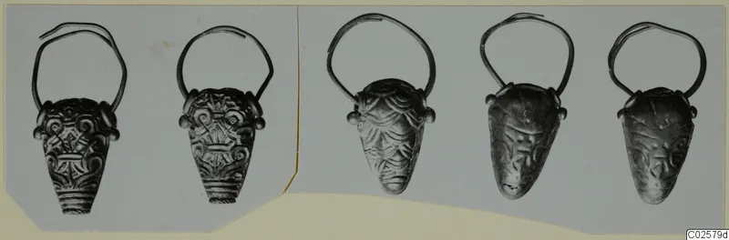 Five gold pendants with wire loops and embossed decoration, arranged in a row on a card mount