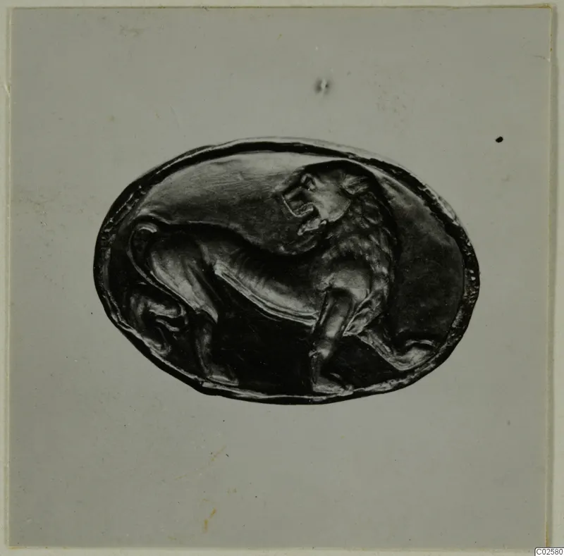 Oval dark bezel with a lion carved in relief, photographed on a pale grey card