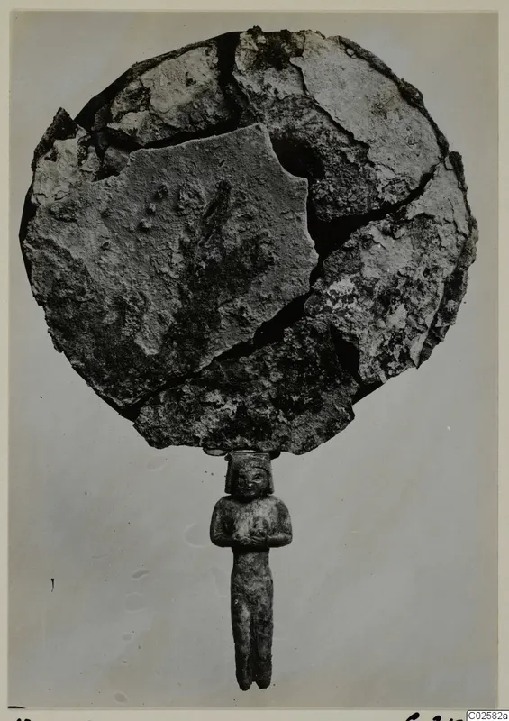 Corroded disc-shaped mirror in broken pieces, with a standing figure forming its handle, from Enkomi