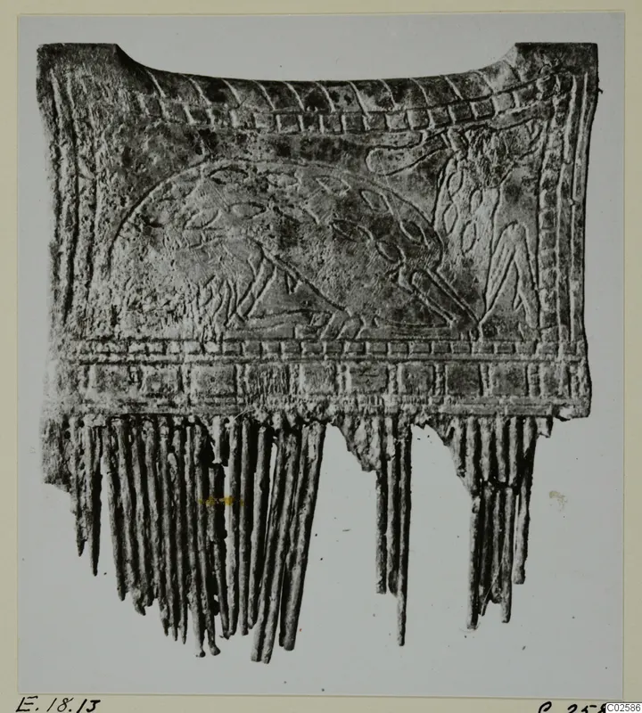 Carved bone object from Enkomi with relief decoration and a fringe of narrow strips along its lower edge.