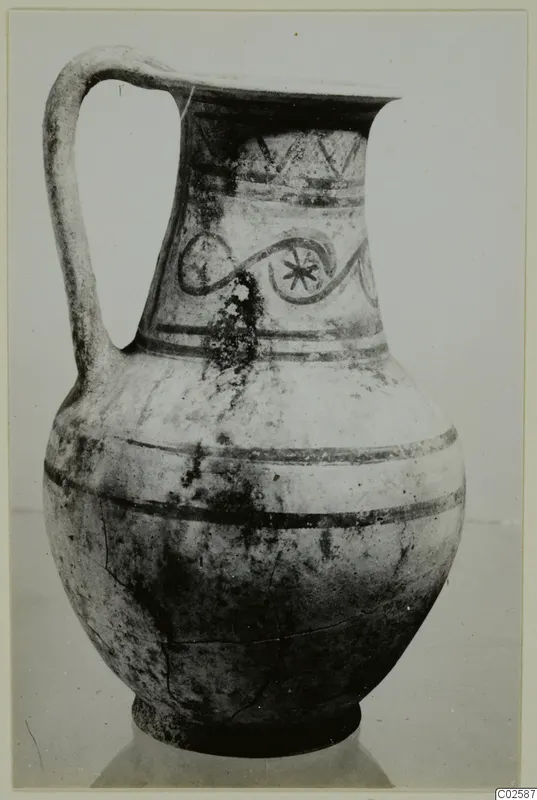Pottery tankard from Enkomi with a strap handle, painted bands, zigzags and a looping motif on the neck.