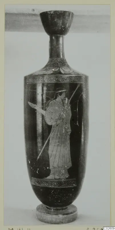 Tall dark vessel with a cup-shaped mouth and a light-toned standing figure holding a spear, on a small base