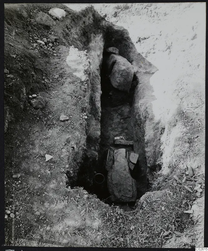 Tomb 422 at Lapithos Kastros during excavation: a narrow cut with large stone slabs and a tomb chamber opening