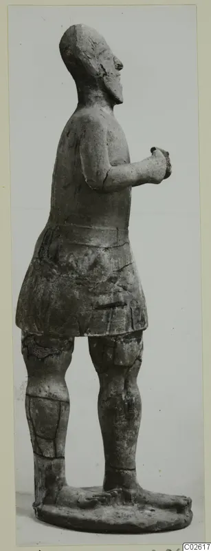 Standing terracotta figure in profile from Ayia Irini, arms bent with hands at the chest