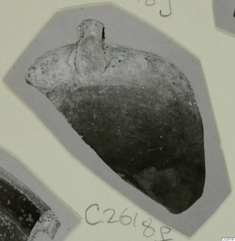Pottery sherd with a short upright projection at the top, photographed on a grey card mount