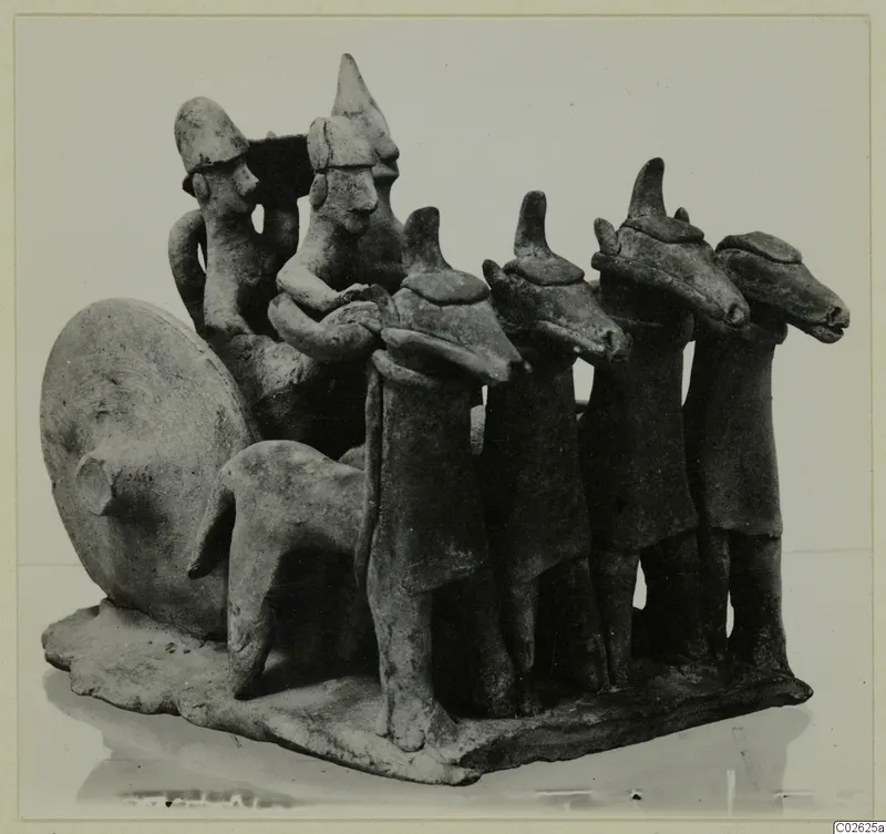 Terracotta group of small figures on a shared base, including a row of four standing figures with animal-like heads and a quadruped.