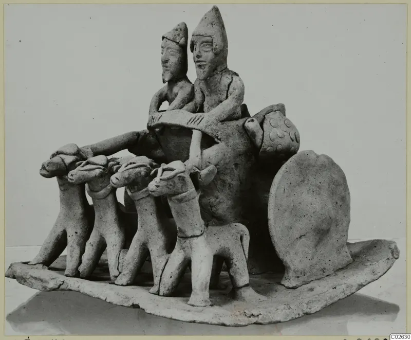 Unglazed clay group of two figures on a cart drawn by four animals, set on an oval base