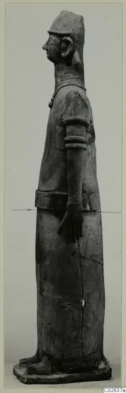 Terracotta Proto-Cypriote II, a tall standing figure seen in profile facing left, in a cap and long robe.