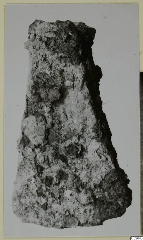 Heavily corroded iron tool from Marion, tapering and crusted with rust, photographed against a grey backdrop