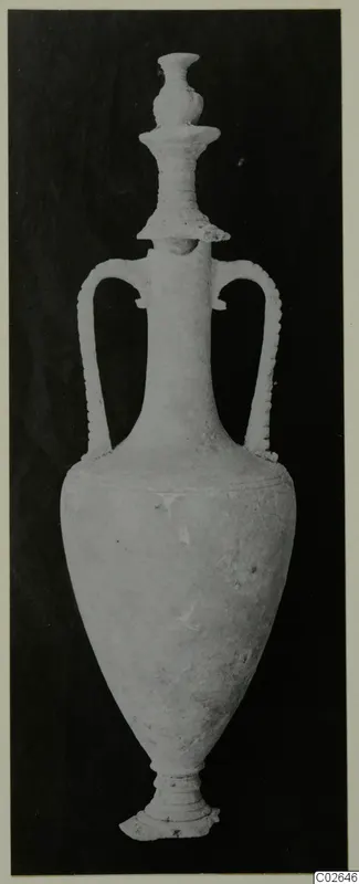 Tall pale stone vessel with two handles and a ribbed stopper, photographed upright on a dark background
