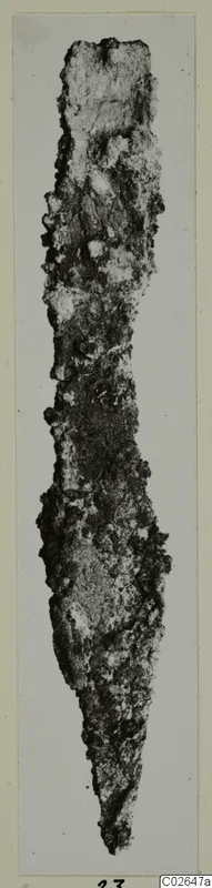 Corroded metal tool from Marion, long and narrow, tapering to a point at the lower end