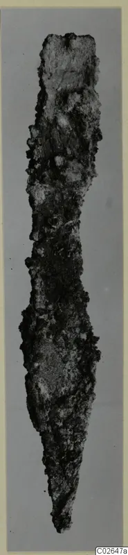 Corroded iron tool with a pointed tip, photographed against a grey backdrop