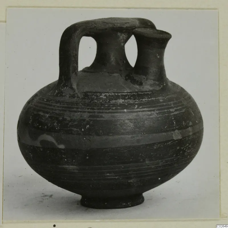 Pottery bowl-jar from Ayios Iakovos with a strap handle and two necks, dark surface with horizontal bands