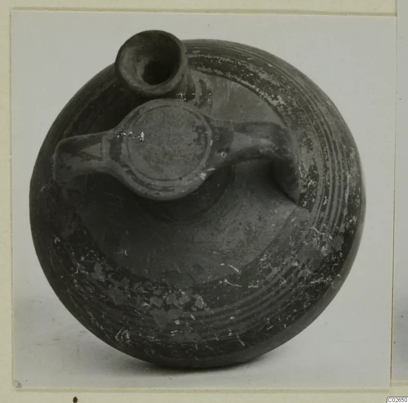 Pottery bowl-jar from Ayios Iakovos with a short neck, a flat lug and loop handles, and bands of concentric lines on its dark surface