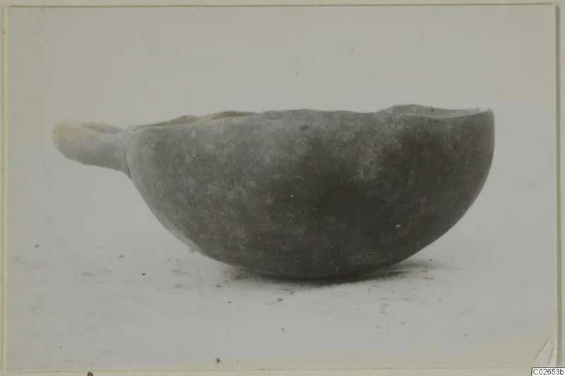 Black slip ware bowl with a single horizontal handle, shown in side view
