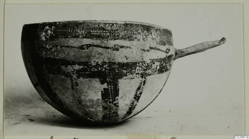 White Slip Ware bowl with a long handle and dark painted bands on a pale body