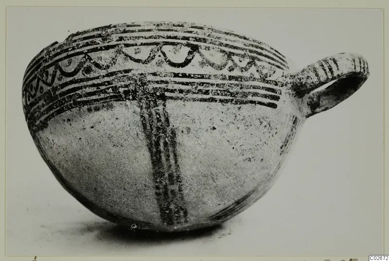 Pottery White Slip Ware bowl from Ayios Iakovos with a single loop handle and dark painted bands and arc motifs