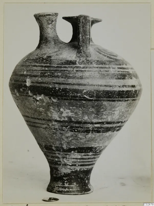Stirrup jar from Ayios Iakovos with horizontal dark bands on its body, photographed on a plain background