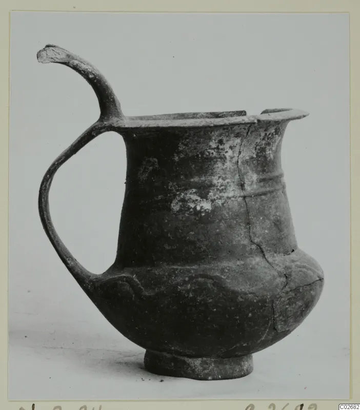 Pottery Base-Ring Ware jug with a tall loop handle and a ring base, shown against a plain background