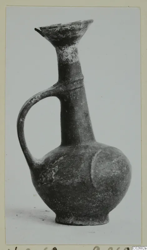 Pottery Base-Ring Ware jug with a flared mouth, tall neck and single handle, photographed against a plain background
