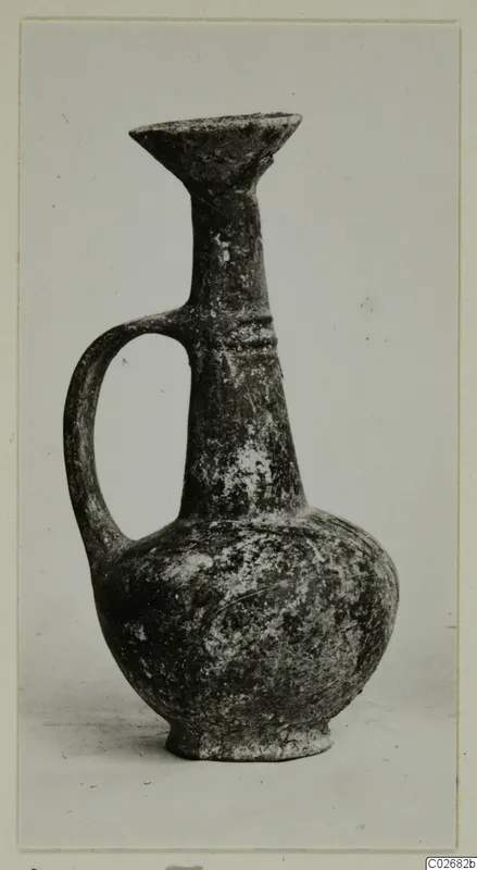 Pottery jug with a single loop handle, a flaring trefoil-like mouth and a rounded body, photographed against a plain background.